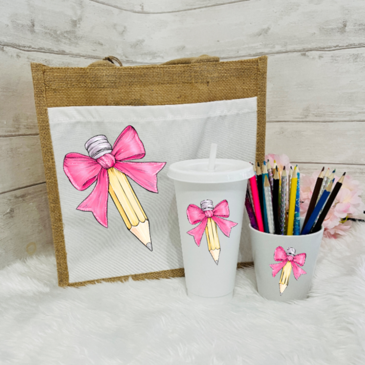 A set of personalized teacher's gifts including a jute bag with a bow and pencil design, a white cold cup with a bow and a pencil pot with a bow in a Pink design.