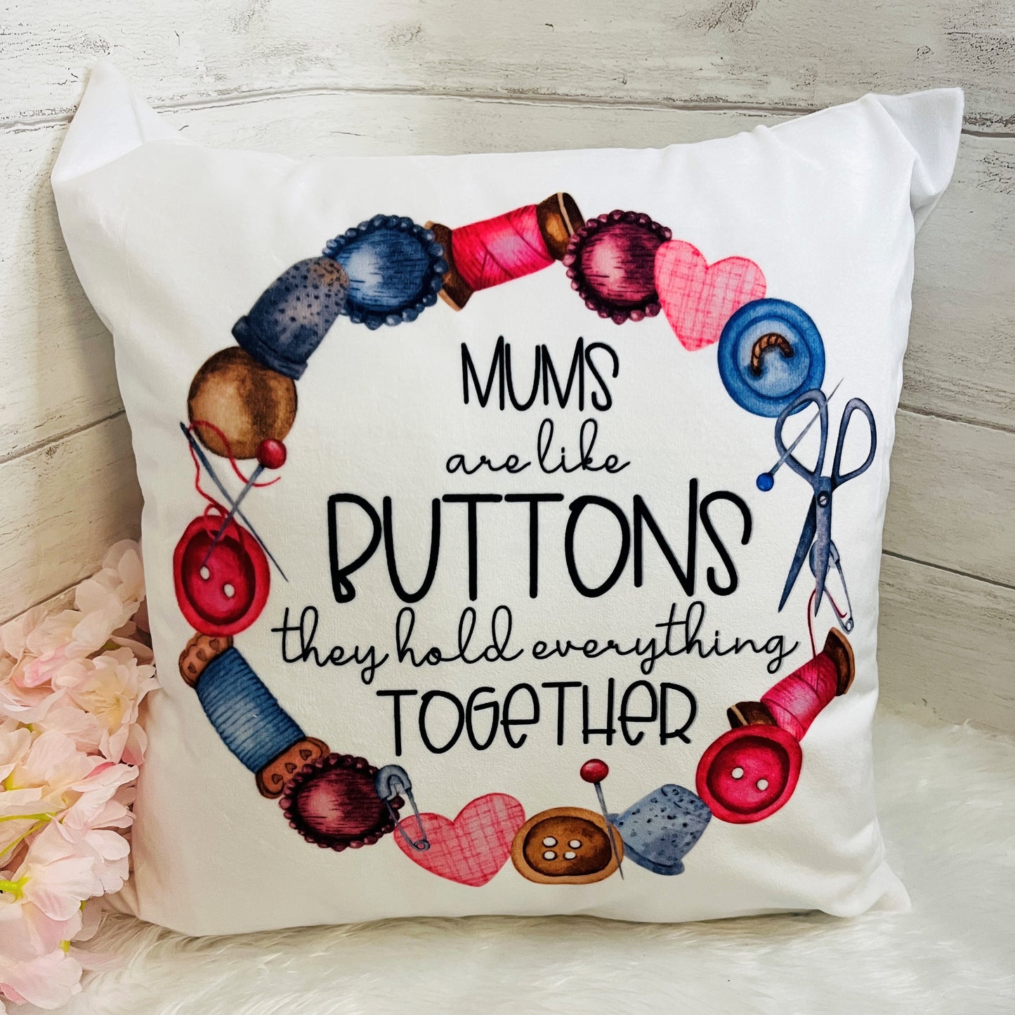 Decorative pillow with sewing-themed design and text on a wooden surface.