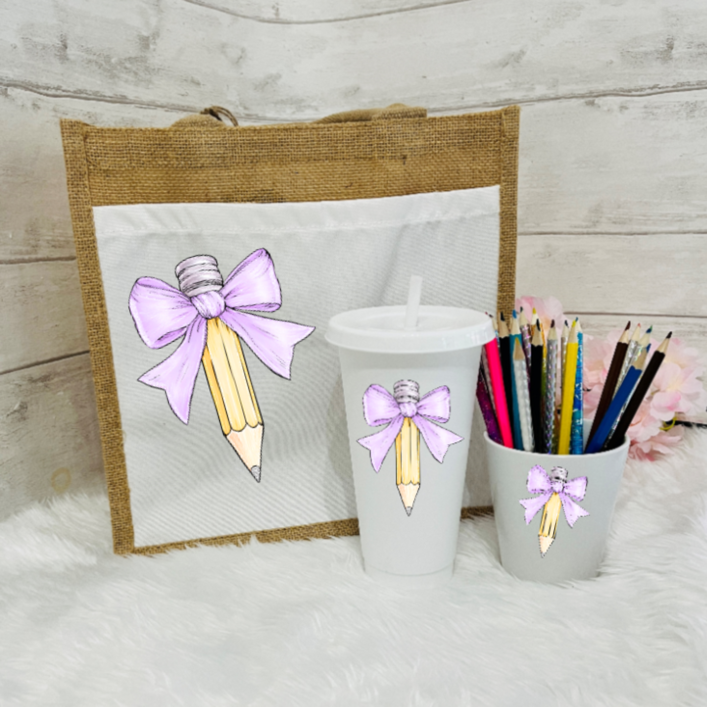 A set of personalized teacher's gifts including a jute bag with a bow and pencil design, a white cold cup with a bow and a pencil pot with lilac bow design.
