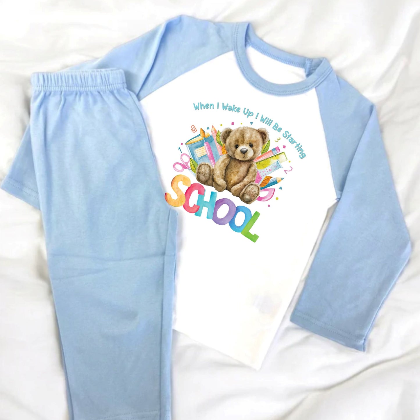 Blue and White Child Pyjamas featuring a teddy bear and 'Starting School' text on a white background.
