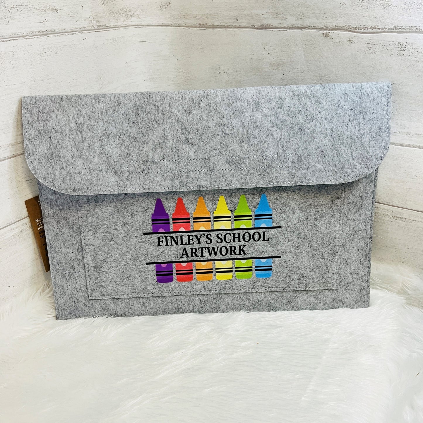 Grey felt folder envelope with colorful crayon design and text on a white surface