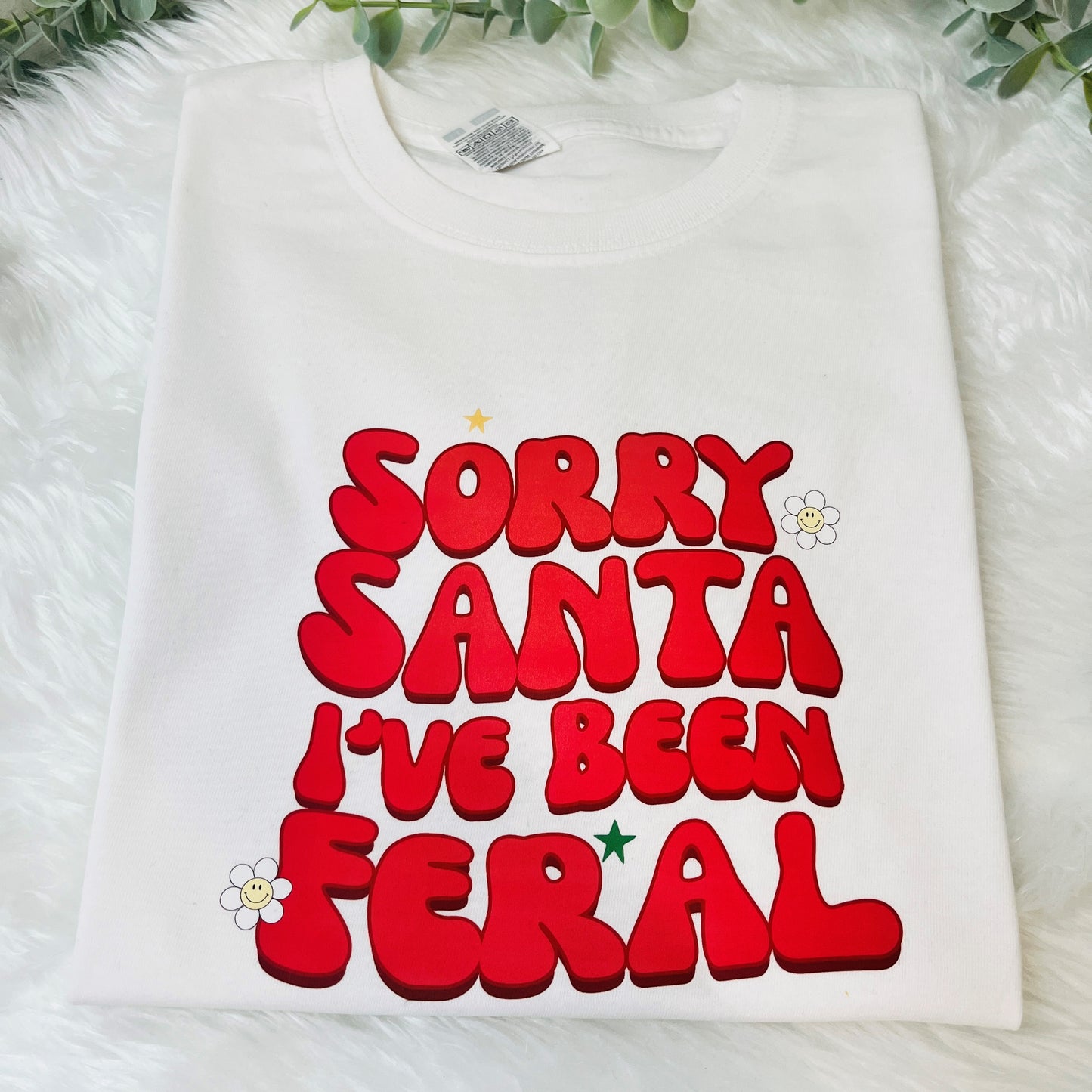 a white childrens t-shirt with the text in bright red saying sorry santa I've been feral'