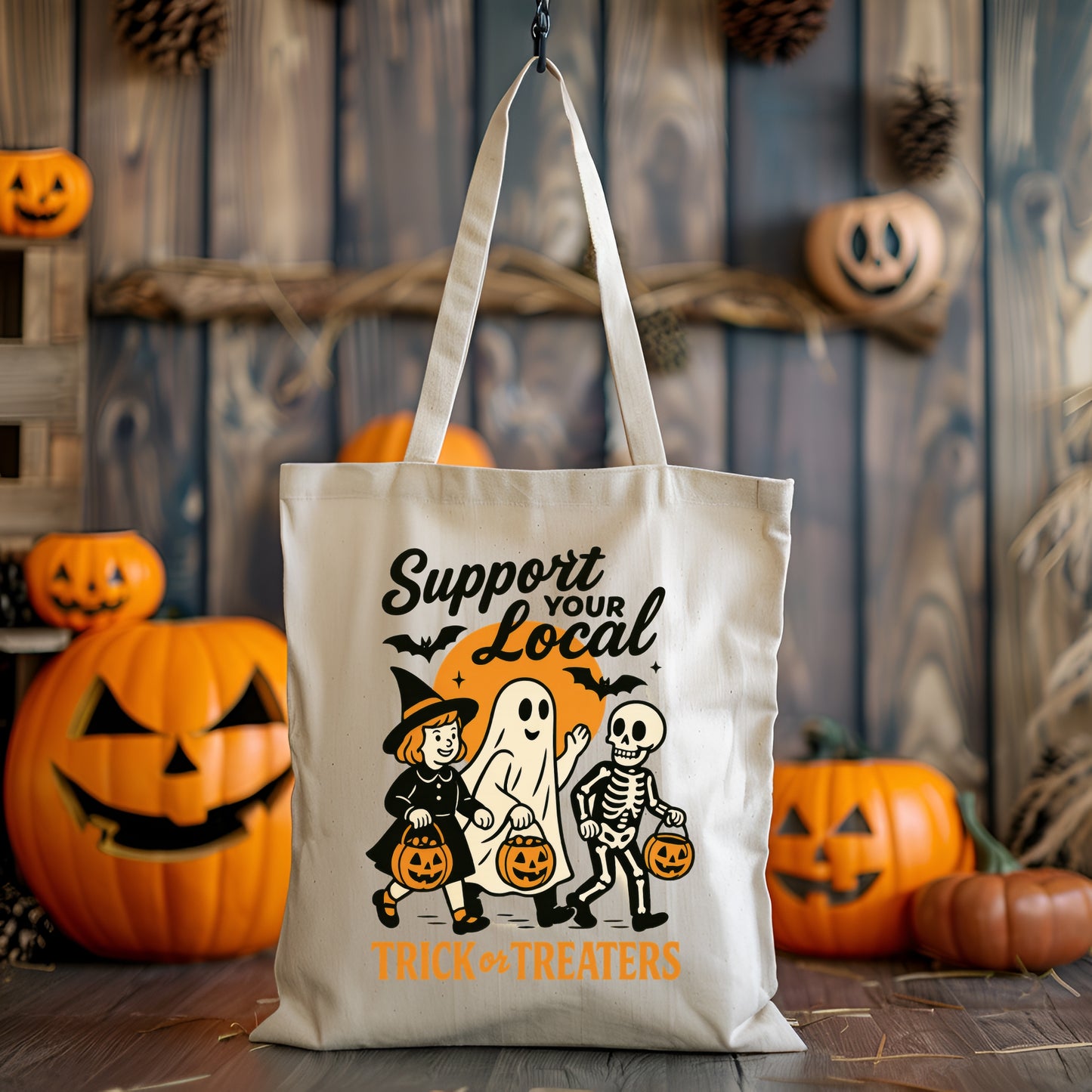Tote bag with Halloween-themed design featuring a witch, ghost, and skeleton with pumpkins in a festive setting.