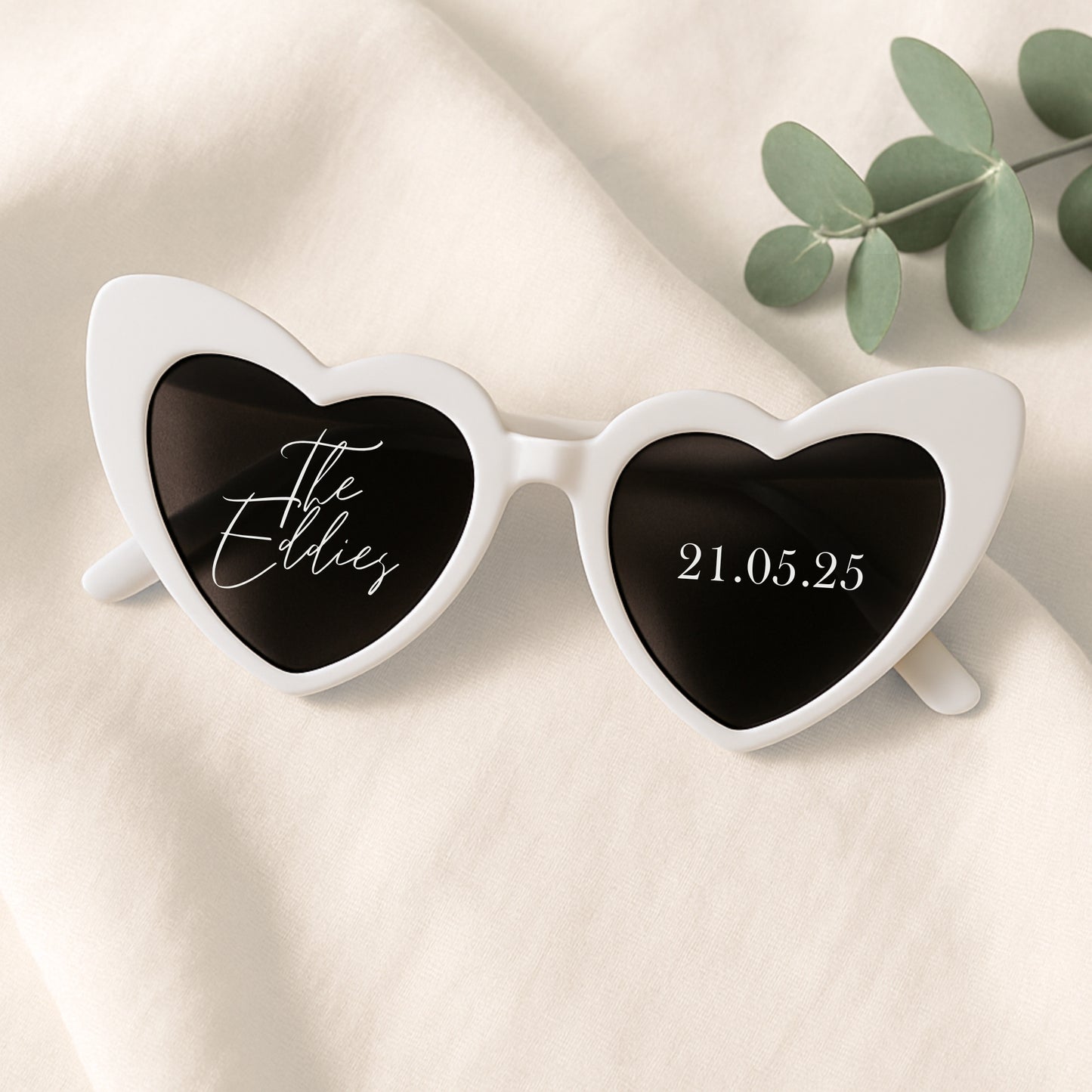 Heart-shaped sunglasses with personalized text on a beige background