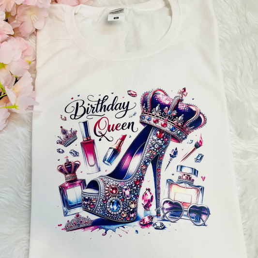 A close up image of a white crew neck t-shirt with a 'Birthday Queen' graphic, featuring Glitter and party-themed elements.