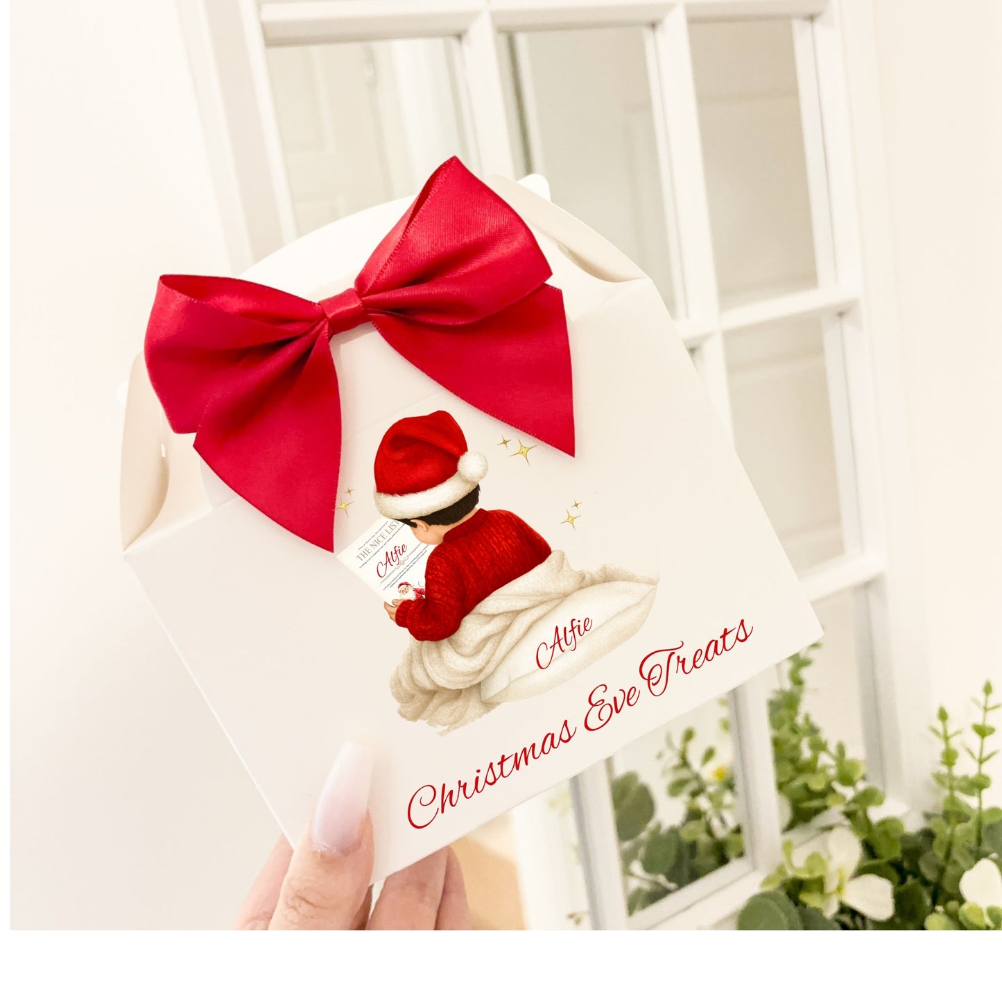 Christmas-themed gift box with a red bow and child in a Santa Claus hat illustration, held against a white background.