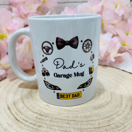 White mug with 'Dad's Garage Mug' text and graphics on a wooden surface 