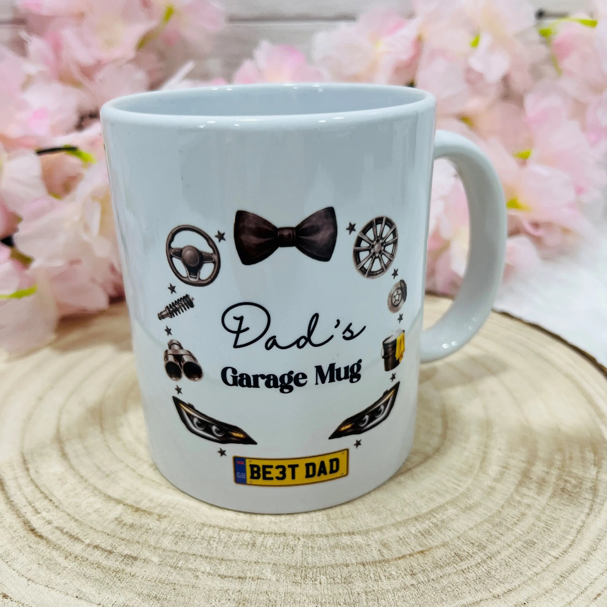 White mug with 'Dad's Garage Mug' text and car-themed graphics on a wooden surface 