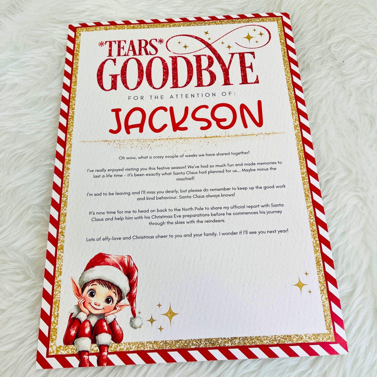 A printed holiday goodbye card for Santa Claus, styled flat on a white faux fur surface. The card features a festive red and gold border, a red and gold 'Tears Goodbye' header, a personalized name field, a Christmas-themed message, and an illustration of an elf in the bottom-left corner.
