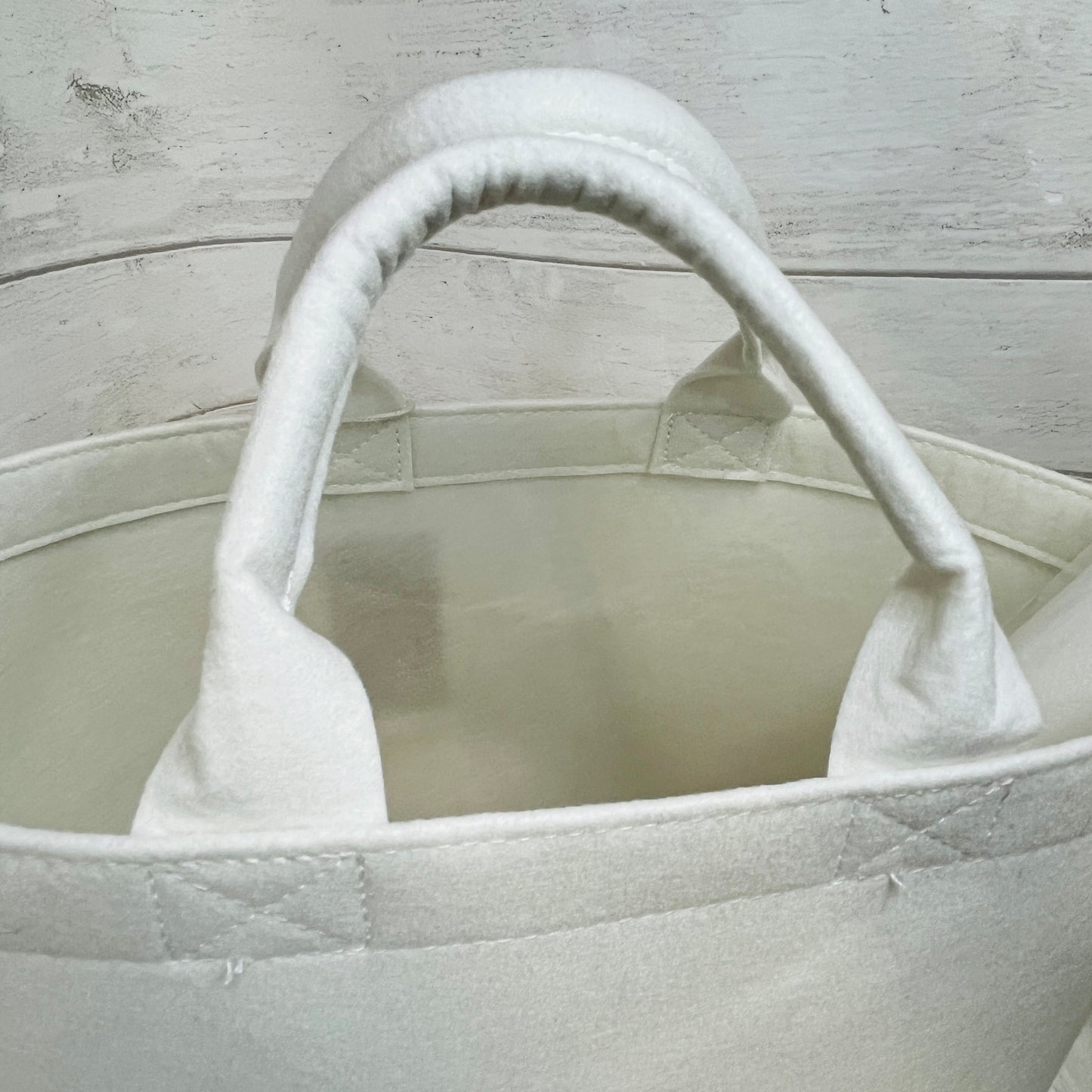 Close-up of a white felt trug handles on a light wooden surface