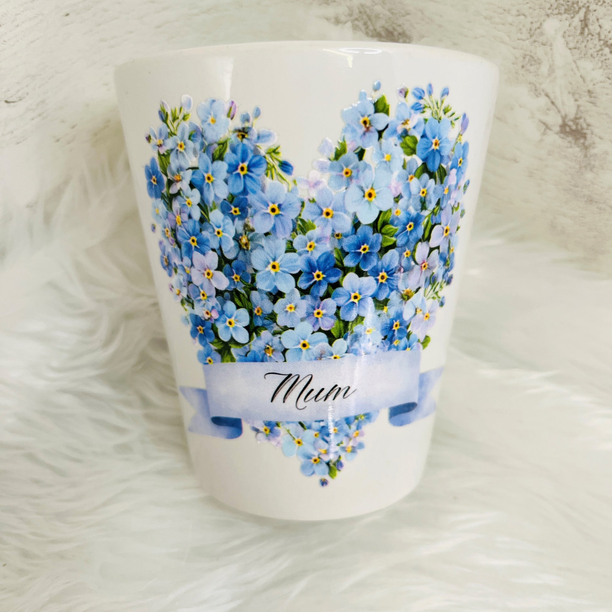 White ceramic plant pot with blue floral design and 'Mum' text on a white background 