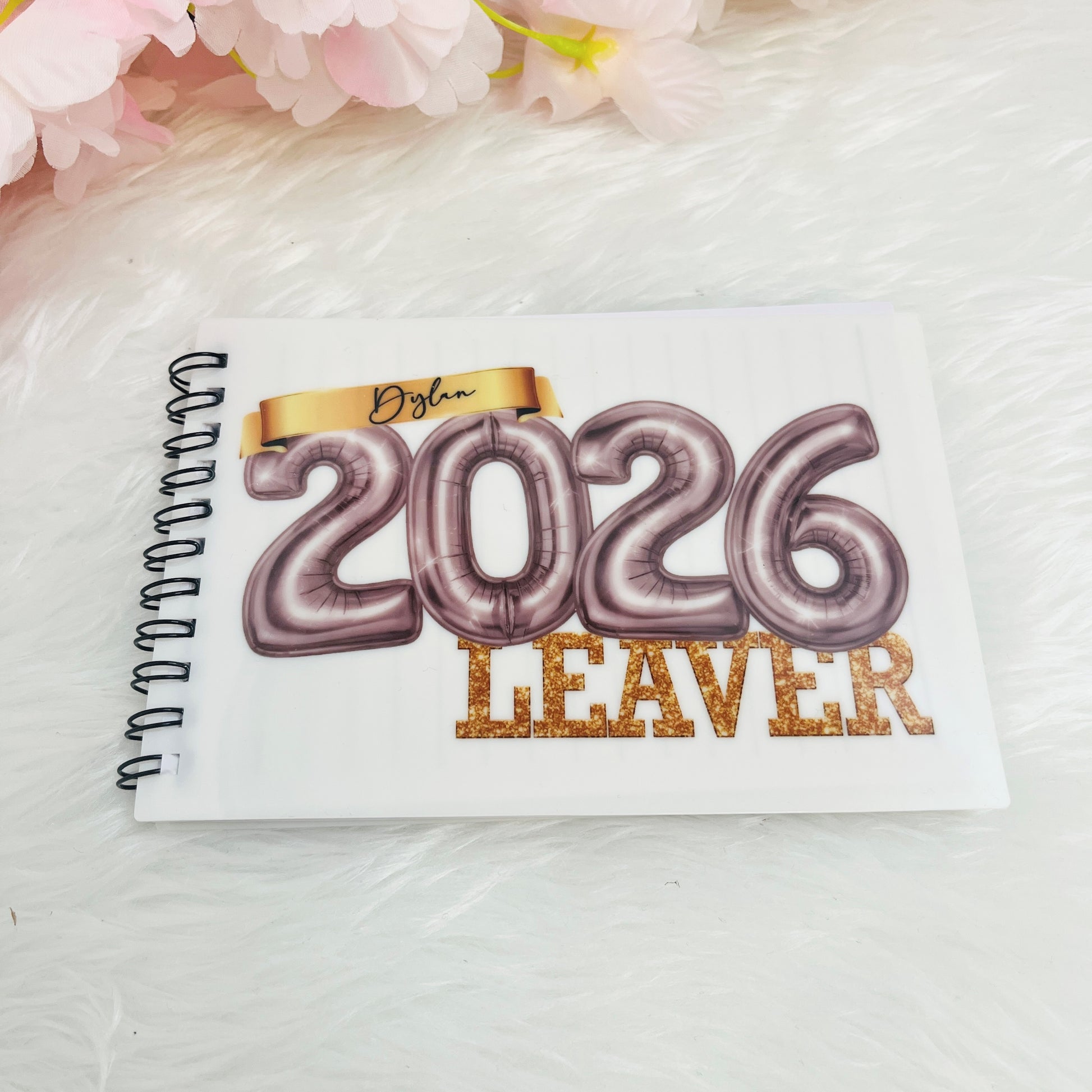 Notebook with '2026 Leaver' design in silver on a white background with pink flowers.