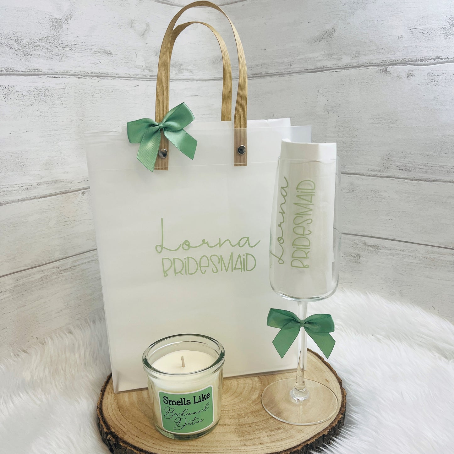 Bridesmaid gift set with a candle, glass, and bag on a wooden surface.