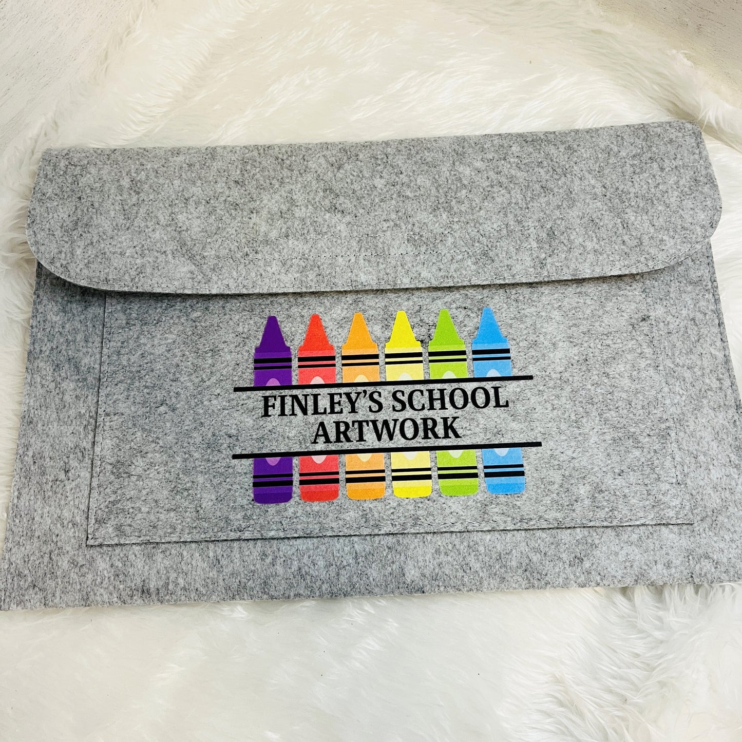 Grey felt envelope folder with colorful crayon design and 'Finley's School Artwork' text on a white background