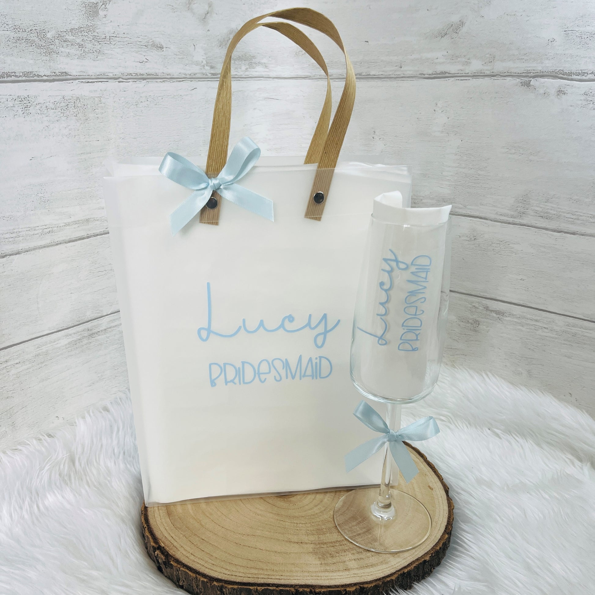 Gift bag and champagne flute with 'Lucy Bridesmaid' text on a wooden surface