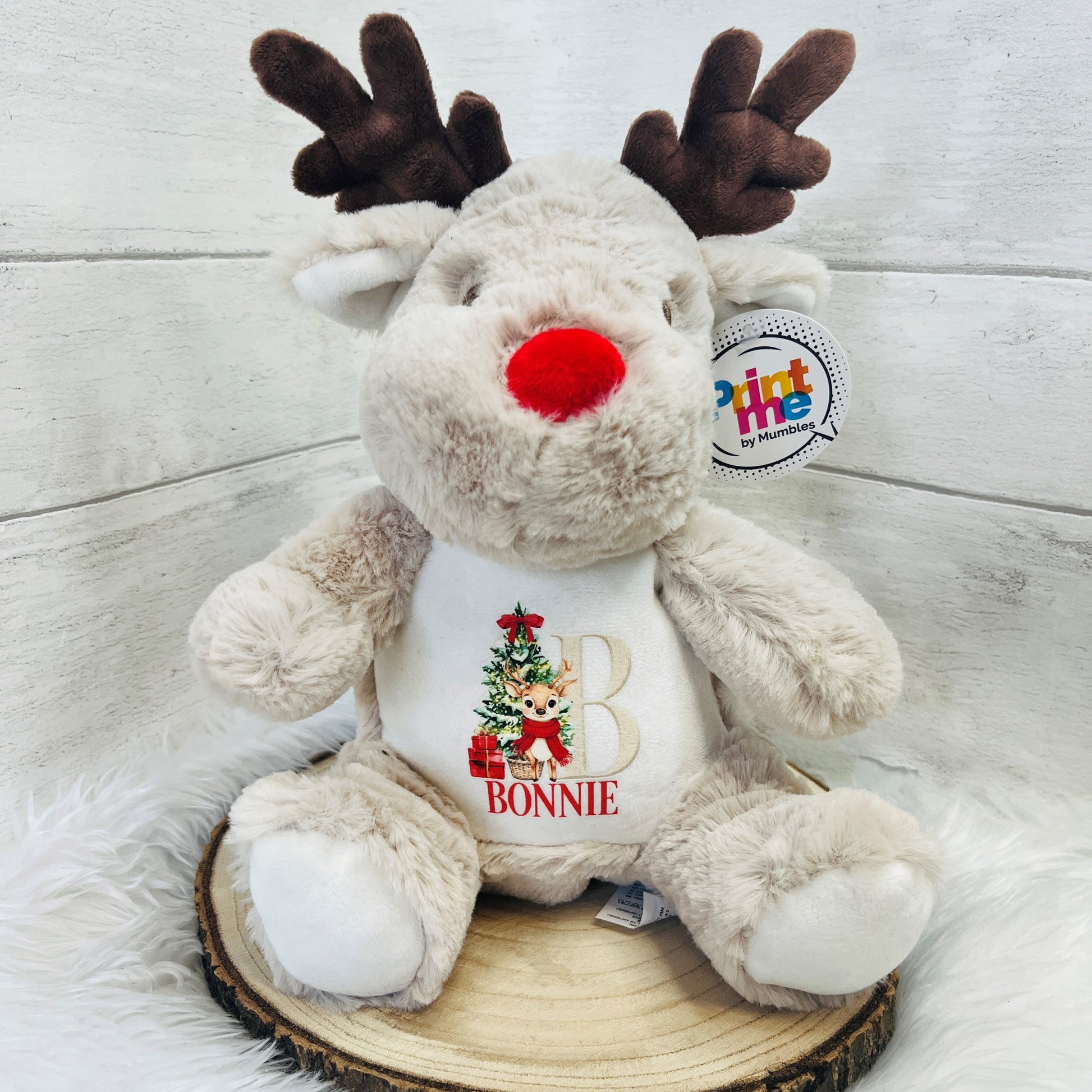 Soft Christmas Reindeer Teddy with personalised name of 'Bonnie' sitting on a wooden log roll against a white background