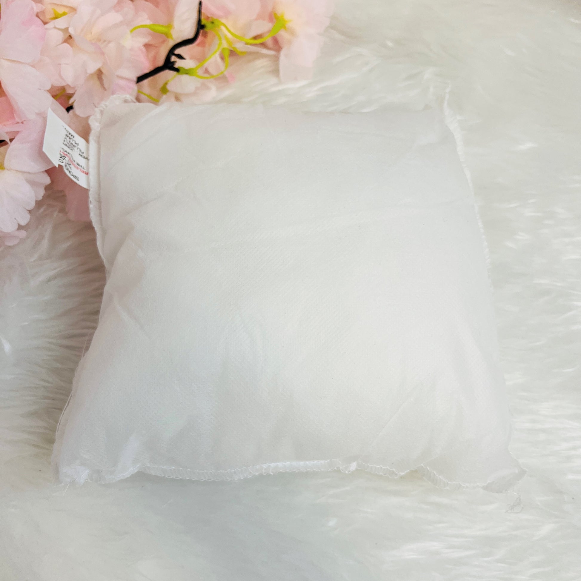 White pillow insert with a tag  background of pink flowers