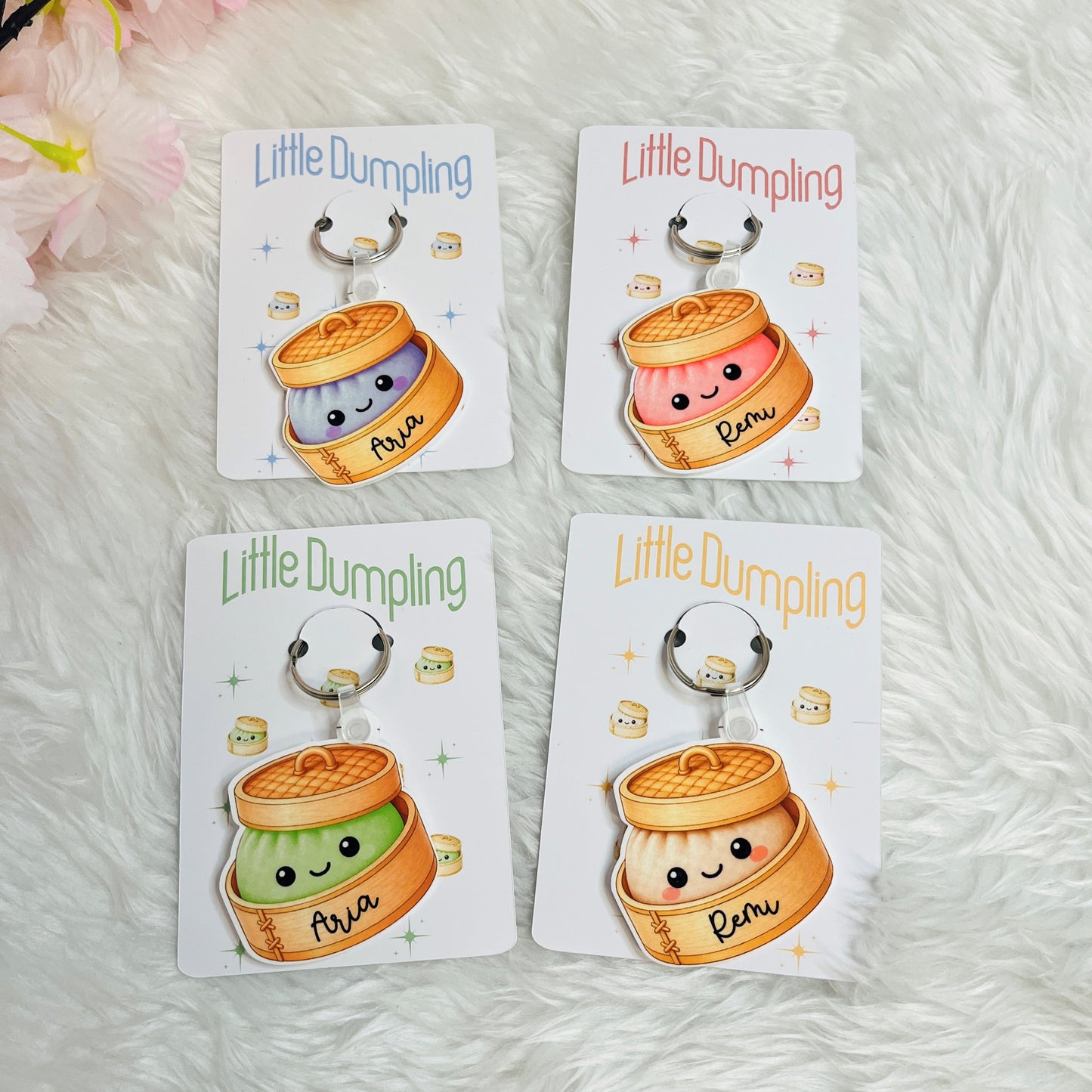 Four 'Little Dumpling' keychains on their packaging with a soft white background.