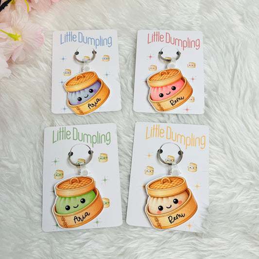 Four 'Little Dumpling' keychains on their packaging with a soft white background.