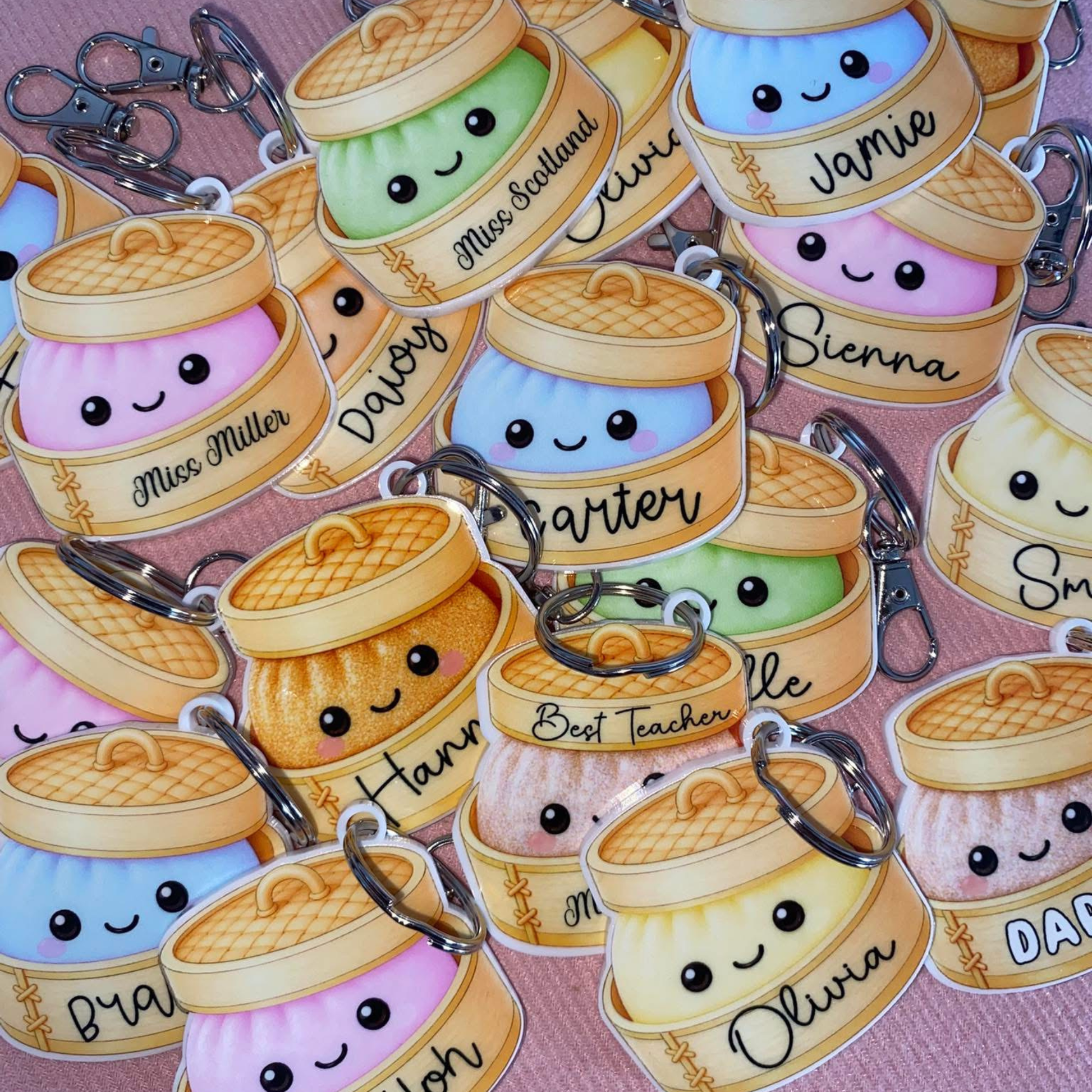 Keychains with cute dumpling designs and personalised names on a pink background