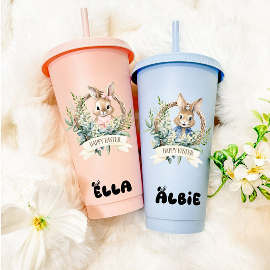 Two 'Happy Easter' tumblers with bunny designs on a fluffy white surface.