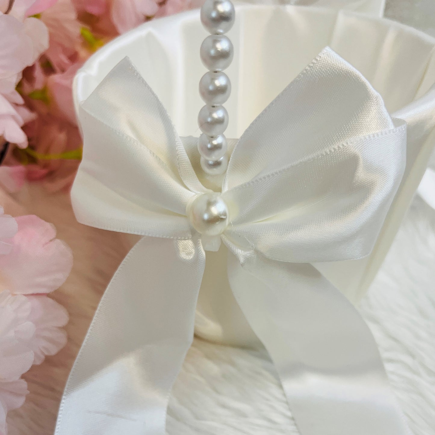 White satin bow with pearl accents on a blurred floral background