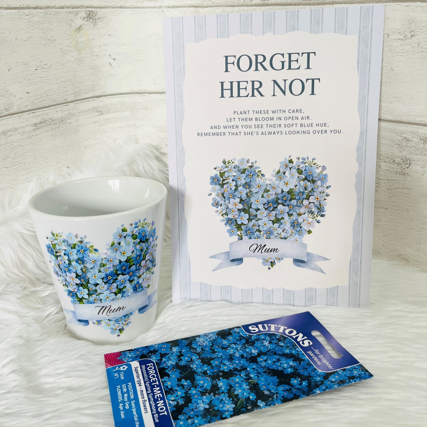 A ceramic plant pot, A5 card poem and pack of forget me not seeds on a white background