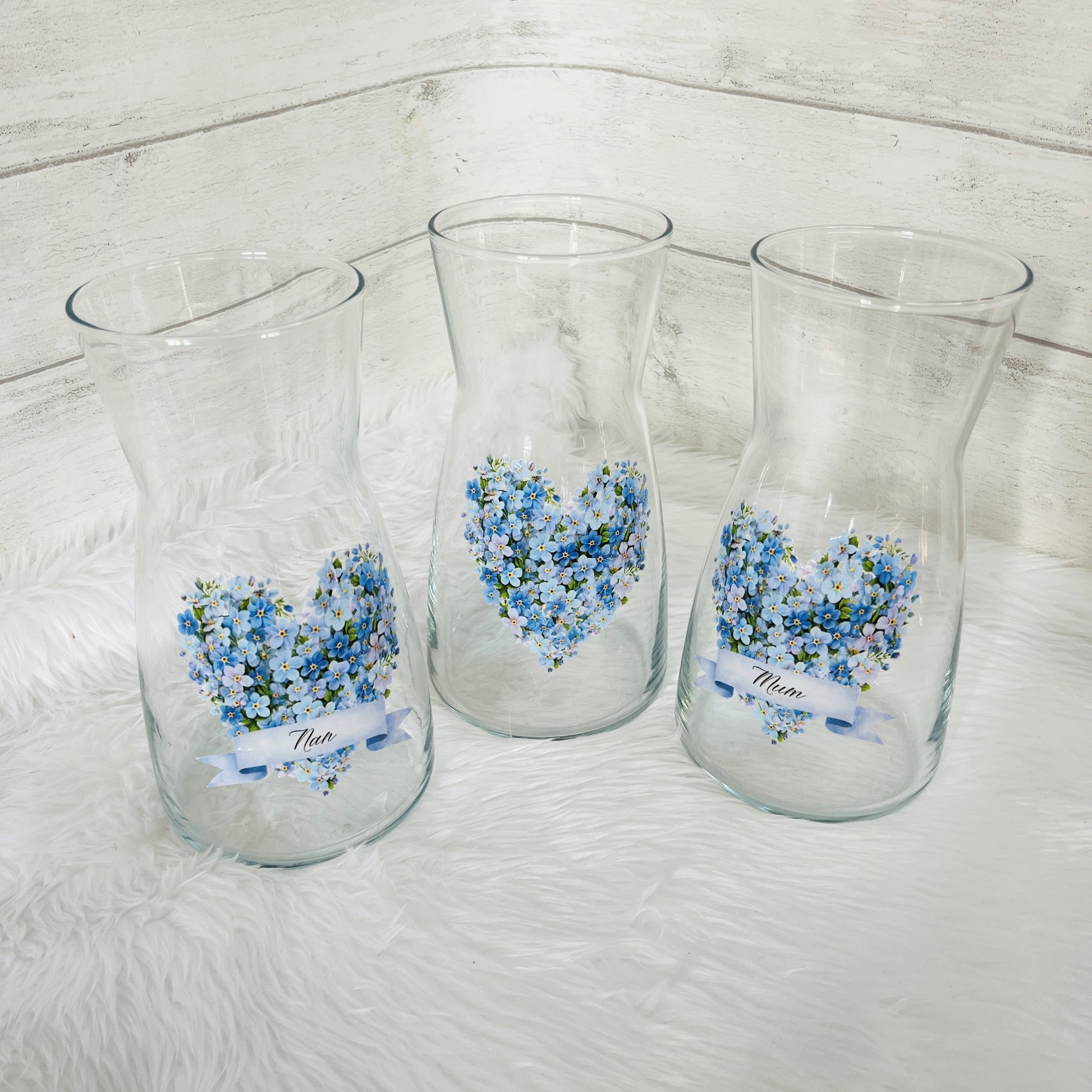 Three glass vases with a forget me not design on the front