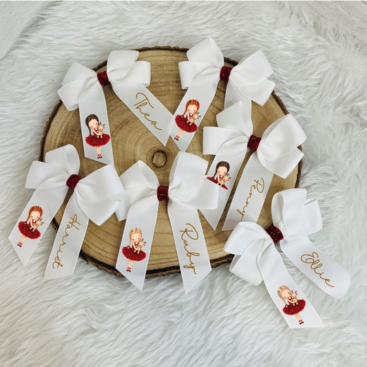 personalised white hair bows arranged on a round wood slice over a white faux fur surface. Each bow has a white ribbon tail printed with a custom portrait of a girl in a red dress, gold script names, and a small dark red glittery center.