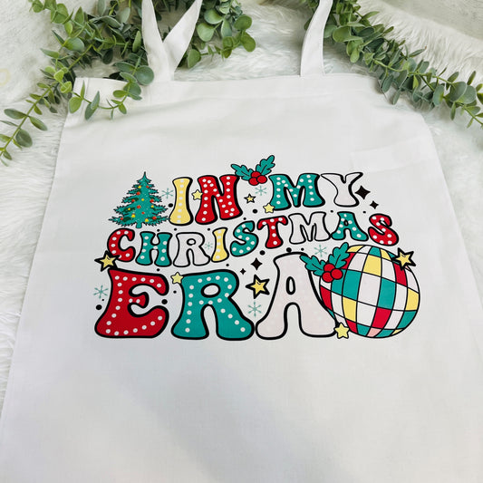 flat lay image of white tote bag with colourful 'in my christmas era' design