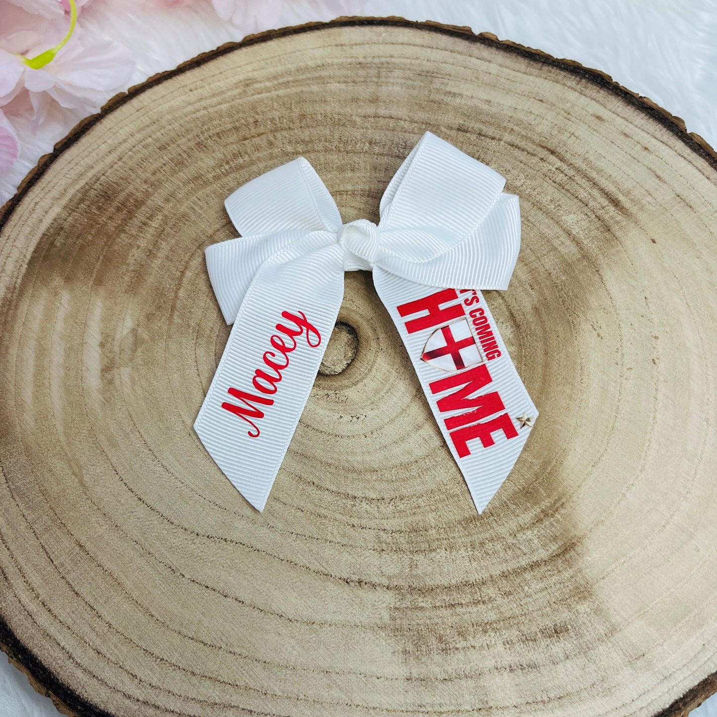 White hair bow with red text on a wooden surface