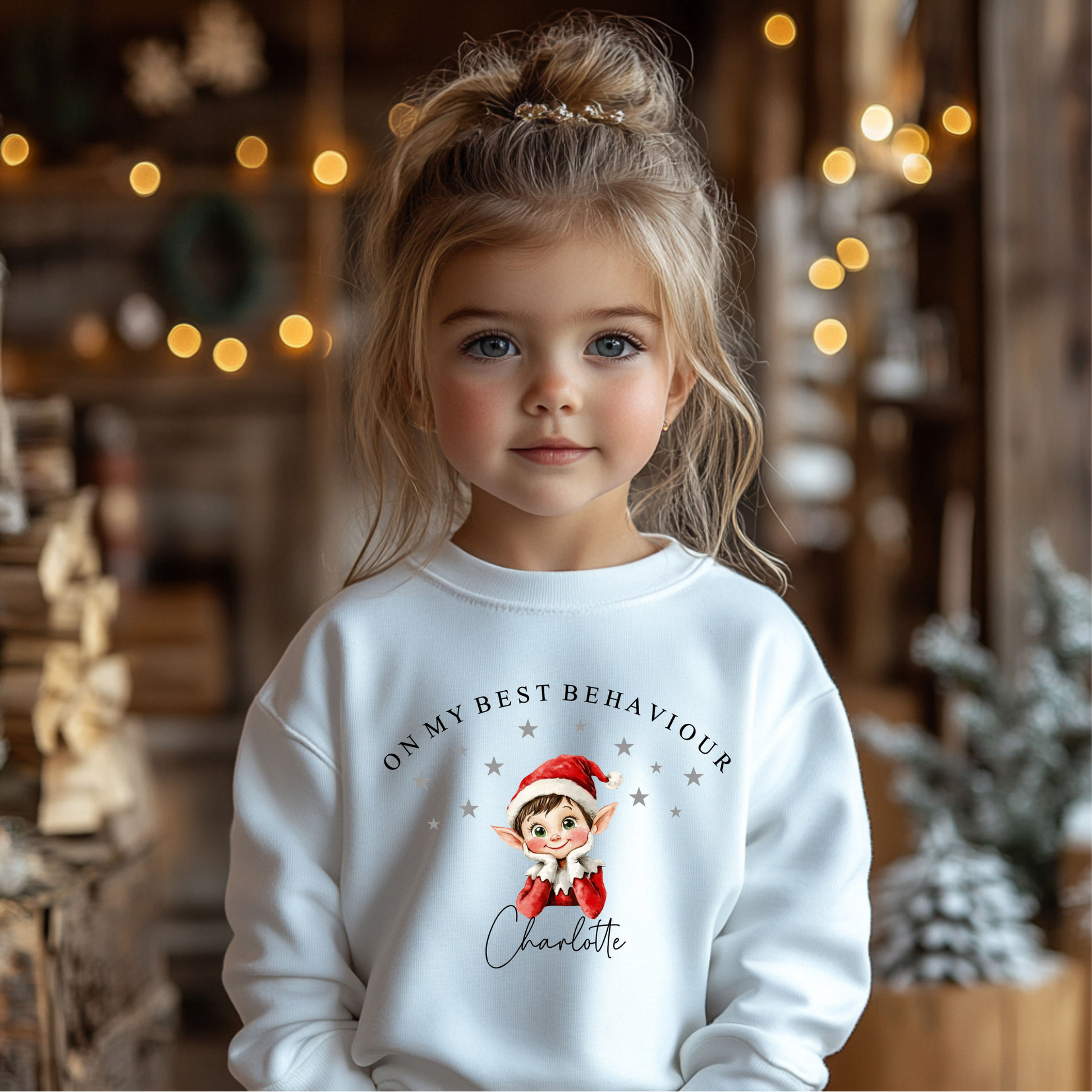Child wearing a white sweatshirt with a Christmas-Elf-themed design in a festive setting.