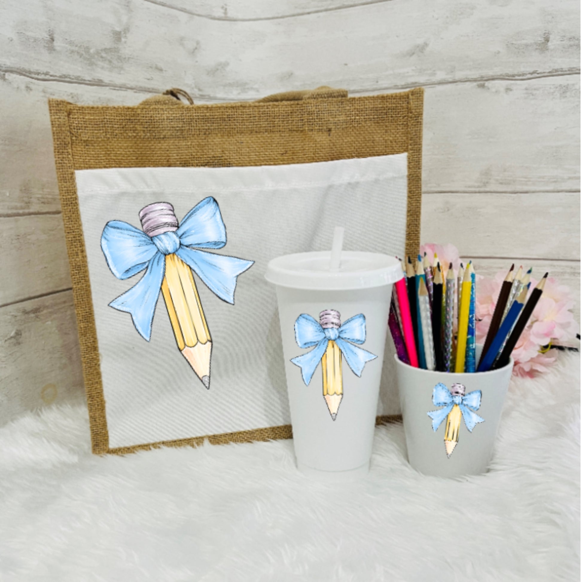 Set of tumbler, pencil holder, and tote bag with bow and pencil design on a wooden surface.