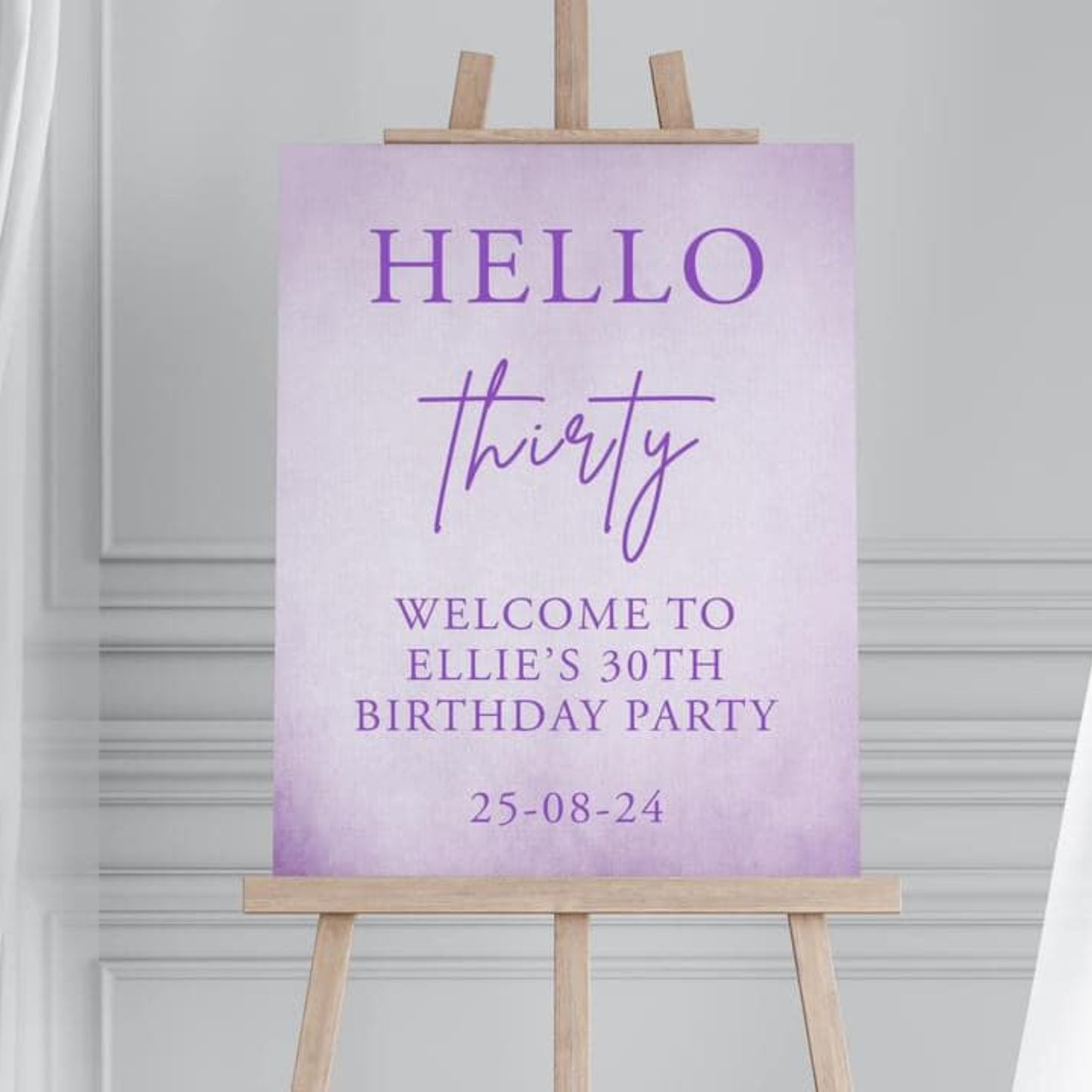 Purple birthday party sign on an easel against a gray wall