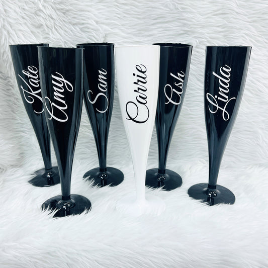 Set of personalised black and white champagne flutes with names on a textured white background
