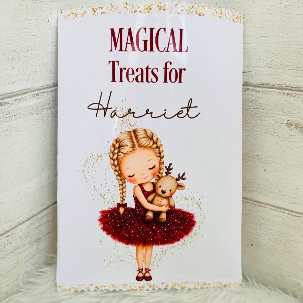 A personalised Christmas-themed treat packet featuring the text 'MAGICAL Treats for Harriet' above an illustration of a blonde girl in a red glittery dress holding a teddy bear, set against a white wood plank background.