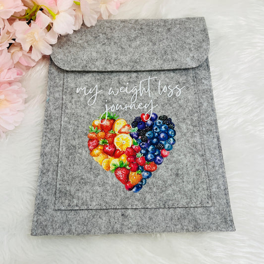 Grey pouch with colorful heart design and 'my weight loss journey' text on a white background with flowers.