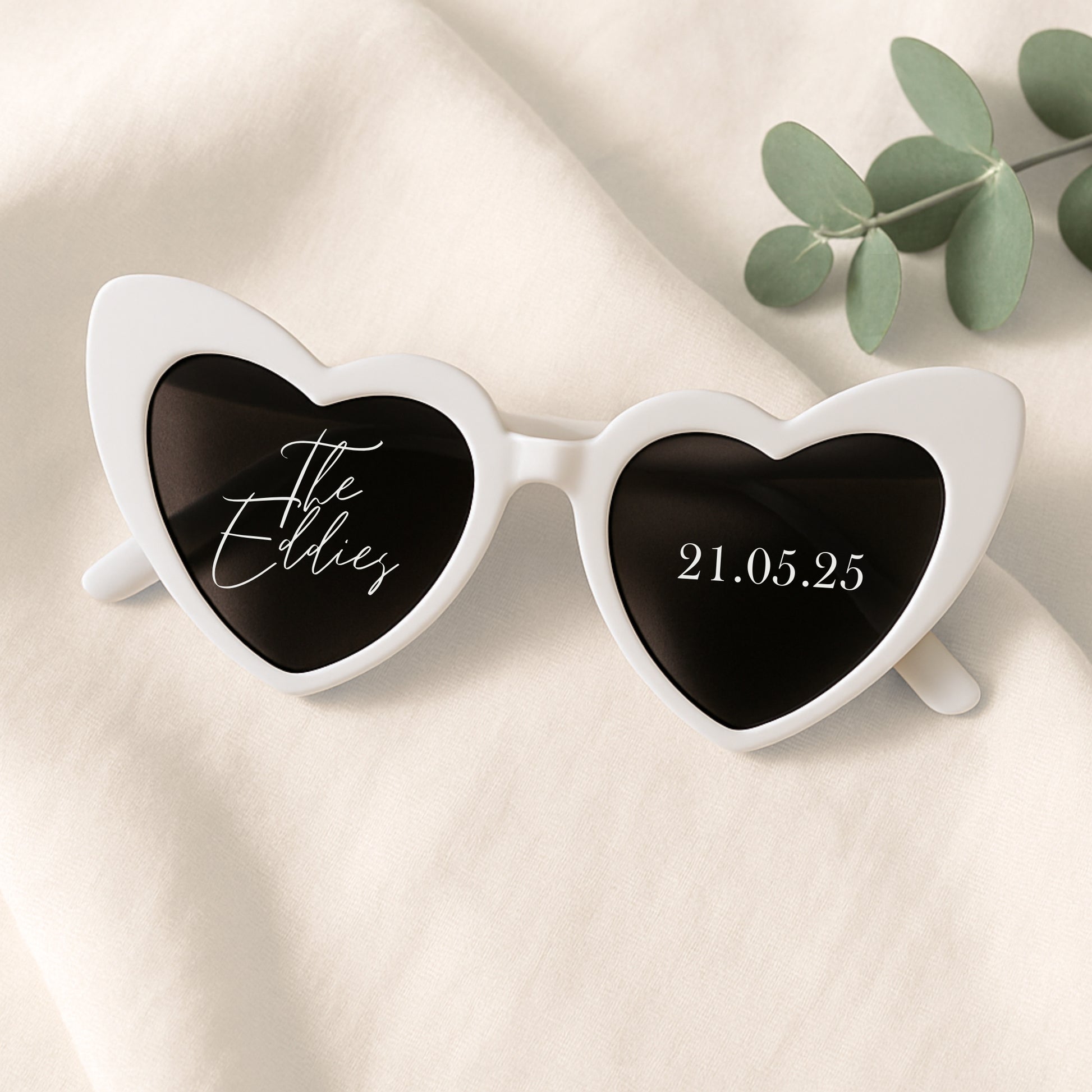 Heart-shaped sunglasses with personalized text on a beige background
